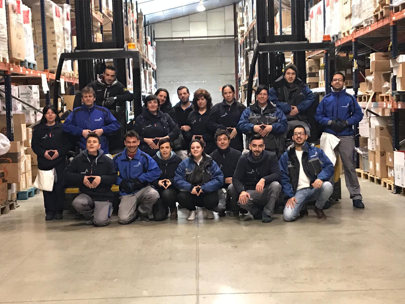 5ea76916-cdd4-4712-99b5-6a7064e452f0 La plantilla de Cogesa se suma a FEDER por las enfermedades raras. Imagen de una de las centrales de logística de Cogesa en la que los trabajadores, con el uniforme corporativo, posan haciendo el gesto "red"